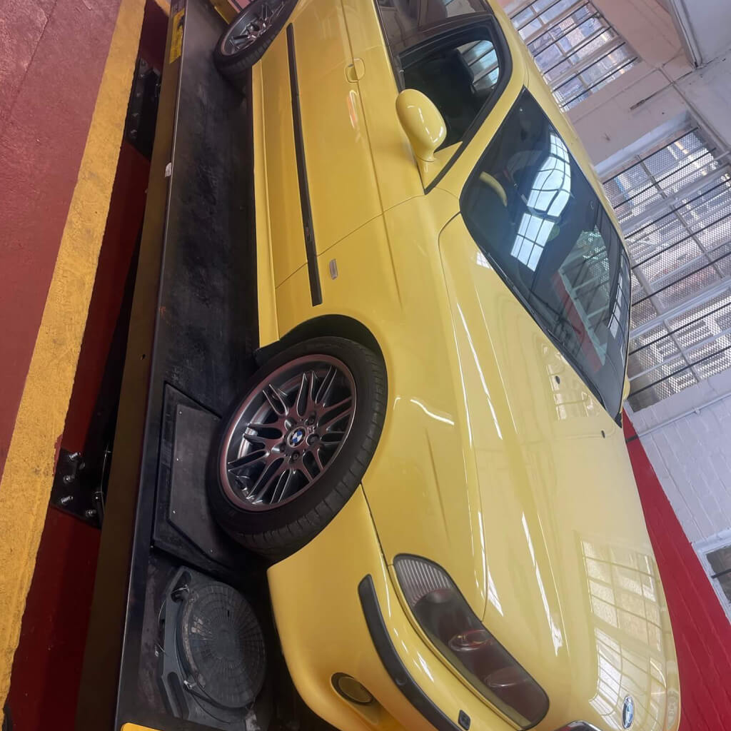 A Yellow car on a ramp inside the workshop